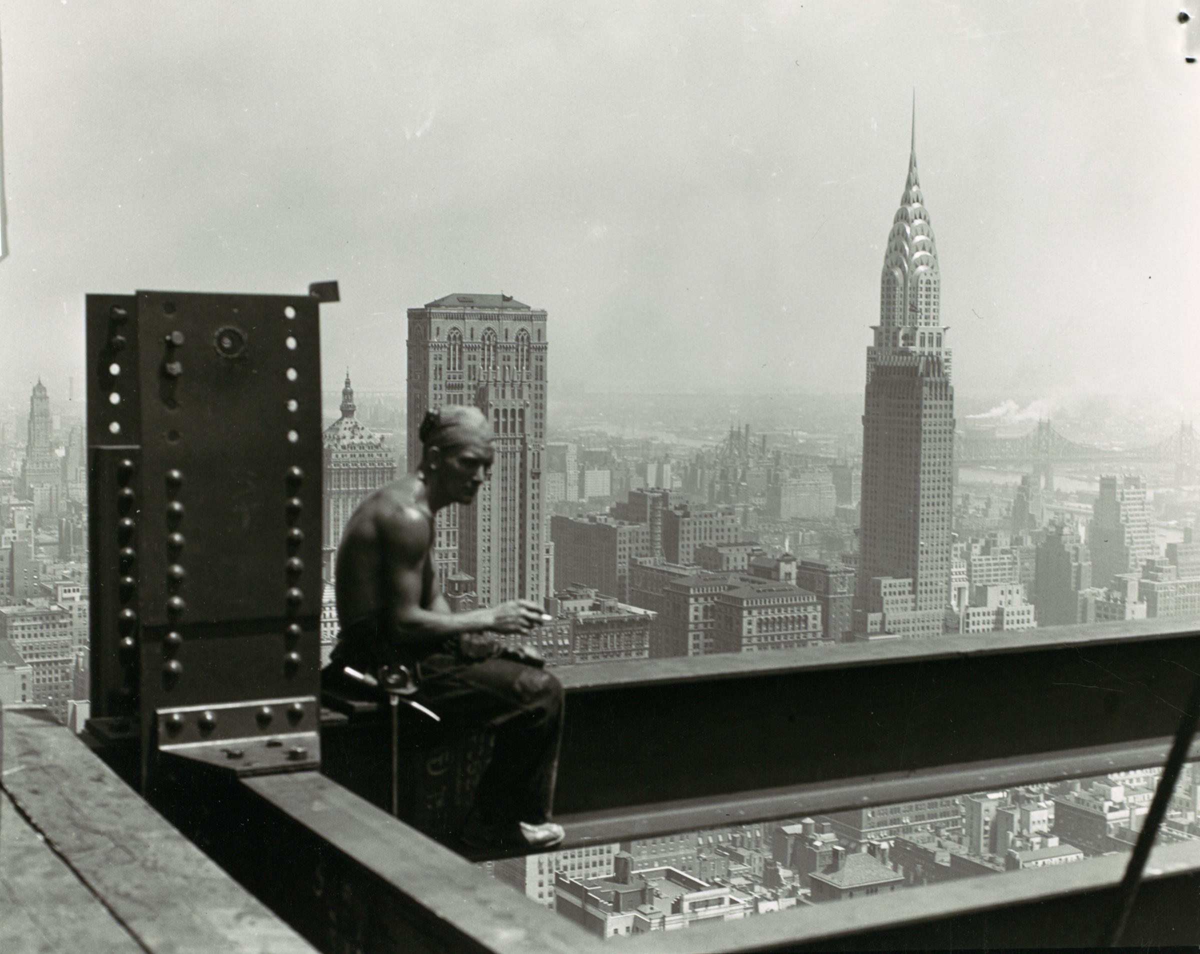 Lewis Hine, Empire State Building (1930). A construction worker sits on a steel beam, the city of New York and the Chrysler Building visible behind.
